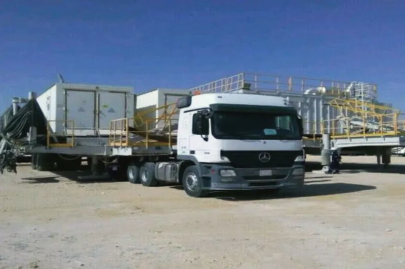 Ajyal truck moving a camp unit on a lowbed in the desert