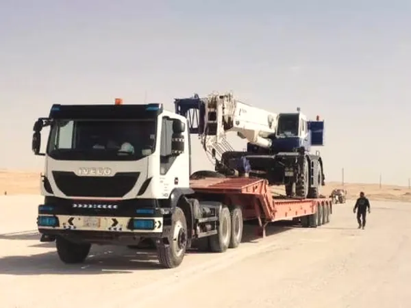 Ajyal prime mover hauling a crane on a lowbed along a desert road