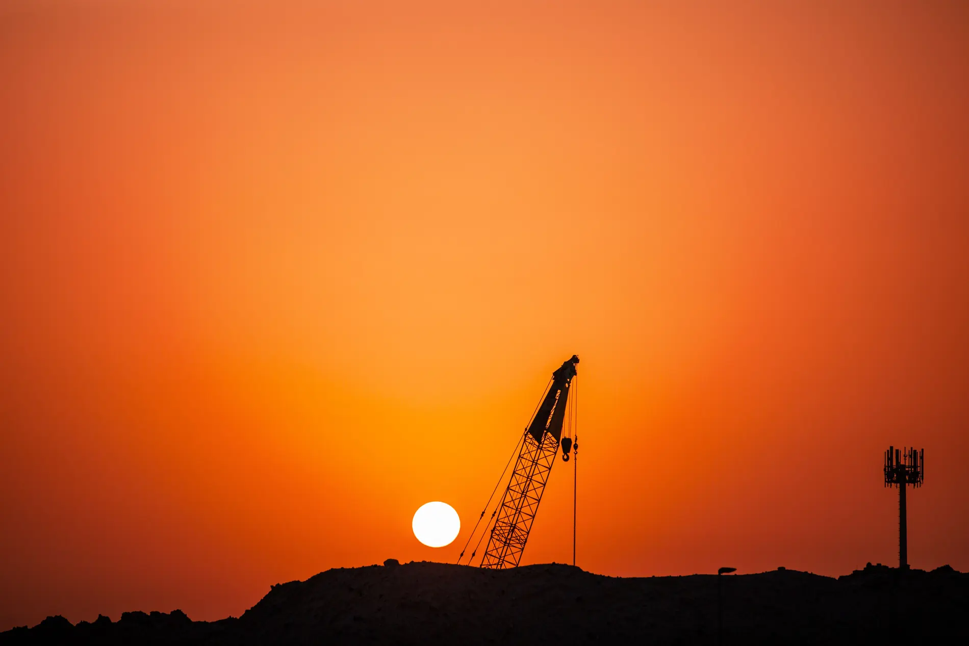Crawler crane silhouetted against a desert sunset