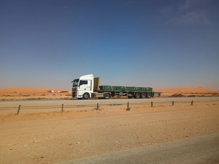 Loaded flatbed truck travelling a desert highway in Saudi Arabia