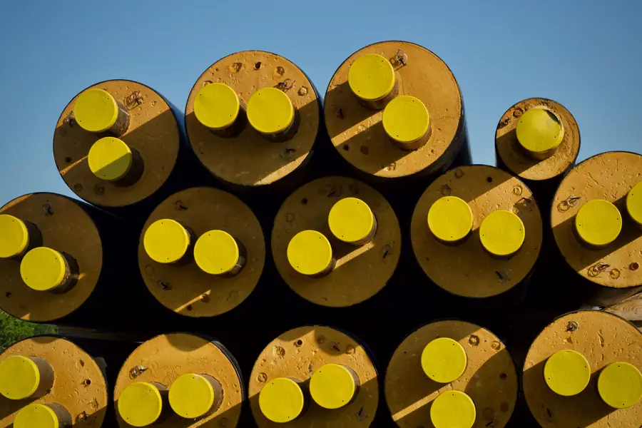 Stacked coated pipe sections with yellow end caps in hard light