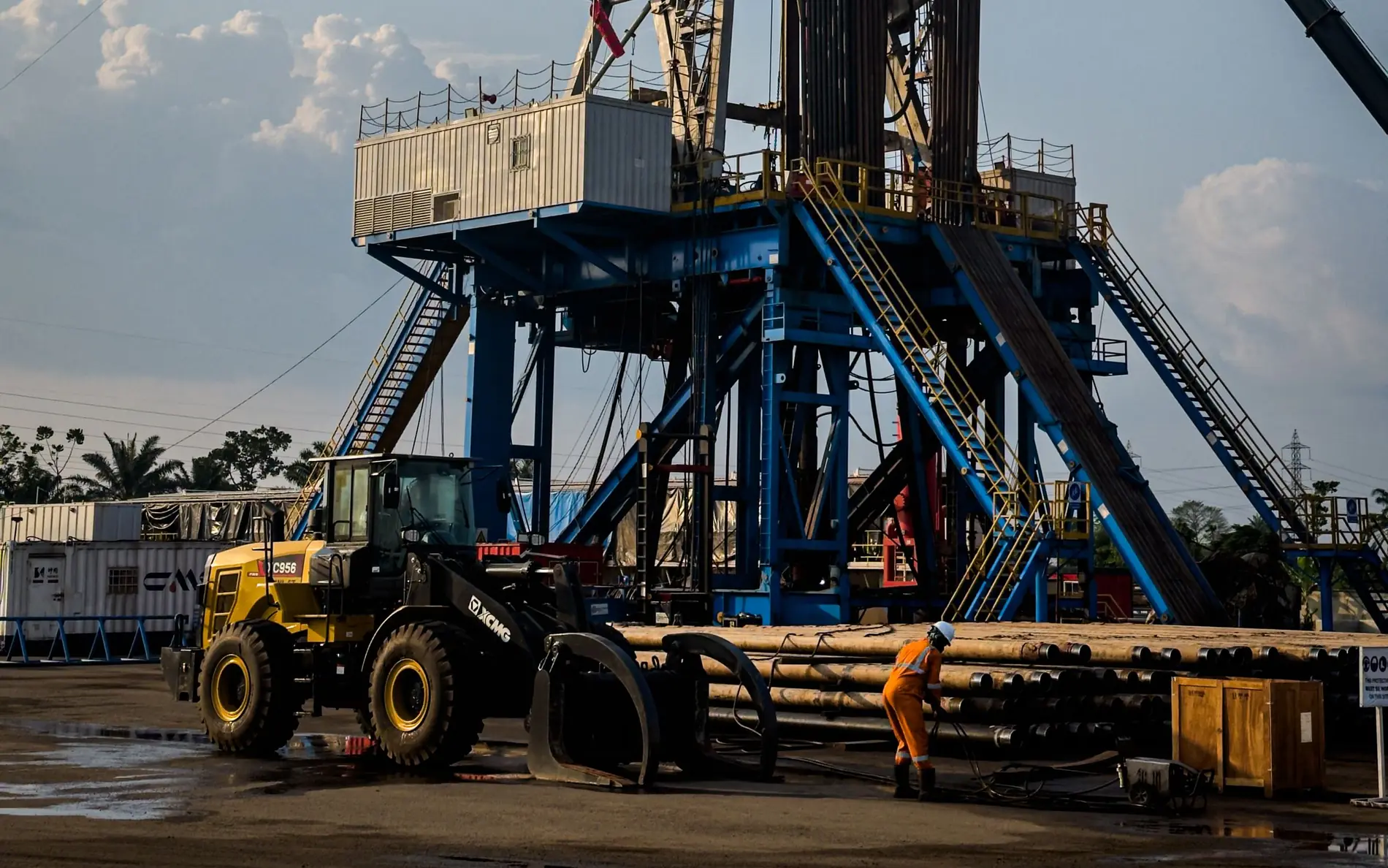 Rig site at dusk with loader and crew between lifts