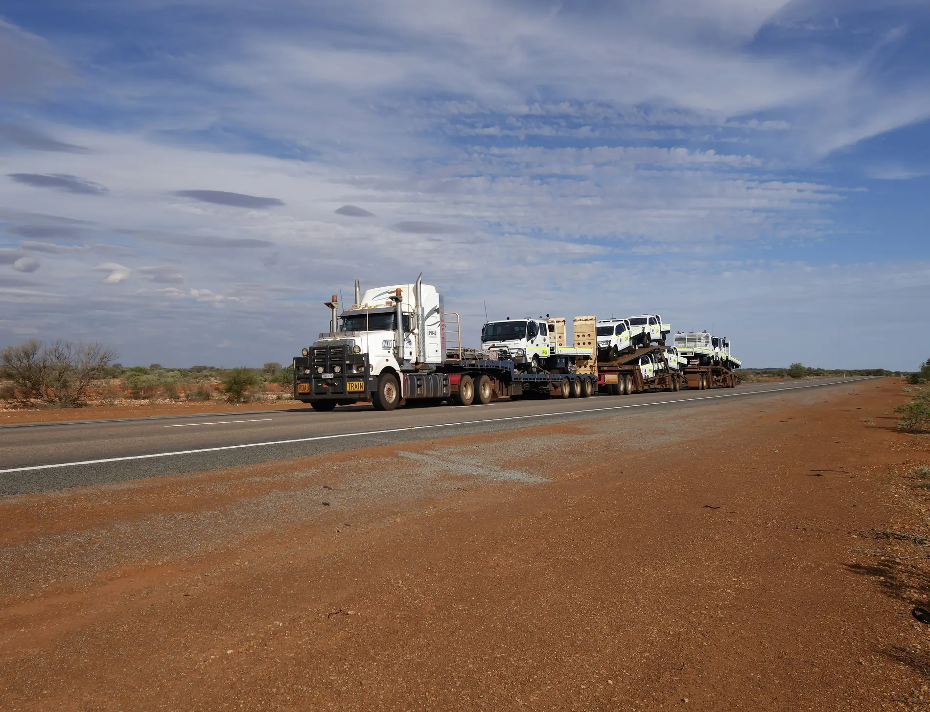 Heavy prime mover hauling a road train across red desert dirt
