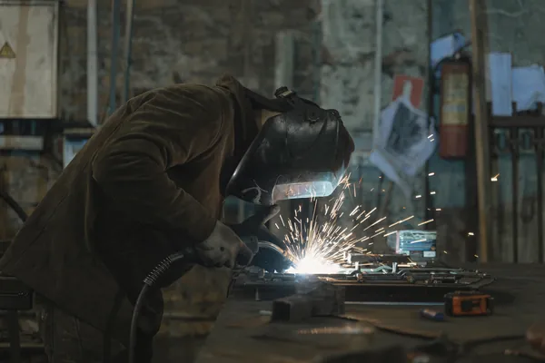 Welder at work in a fabrication workshop, sparks flying