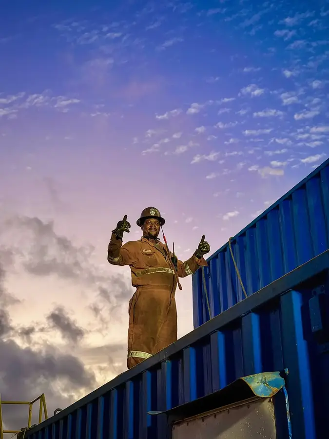 Crew member signalling thumbs-up at dusk on an industrial site
